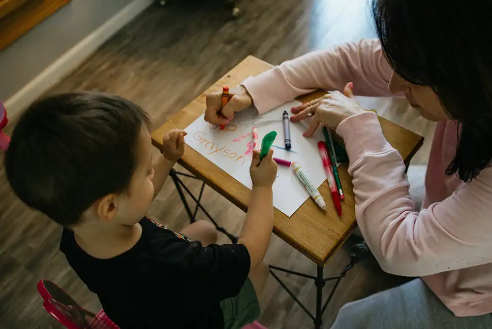 A young boy and a teacher in a daycare classroom.