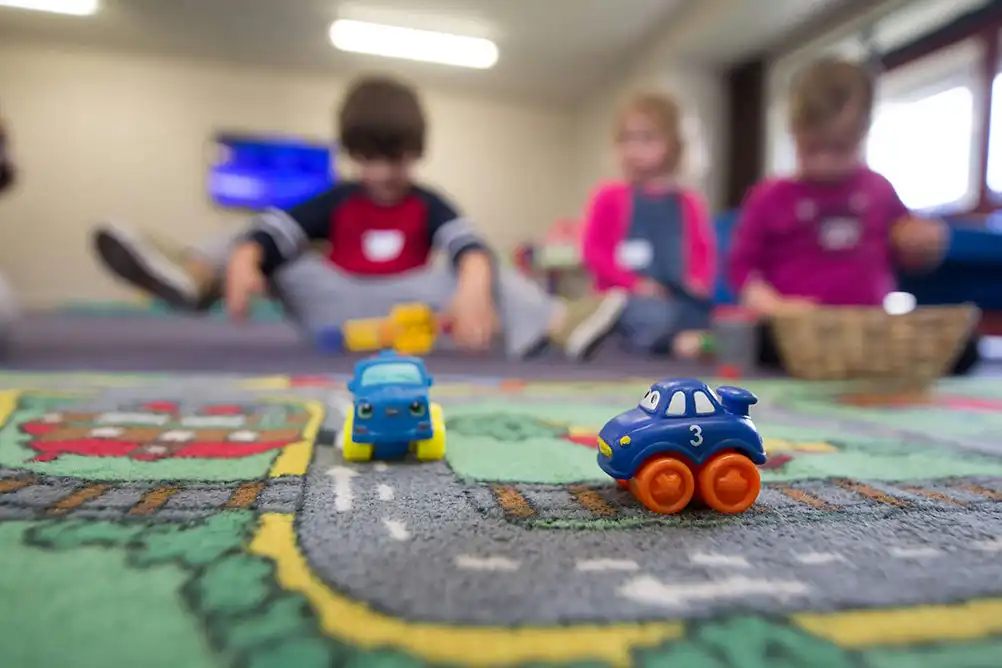 Three children playing in a preschool room.