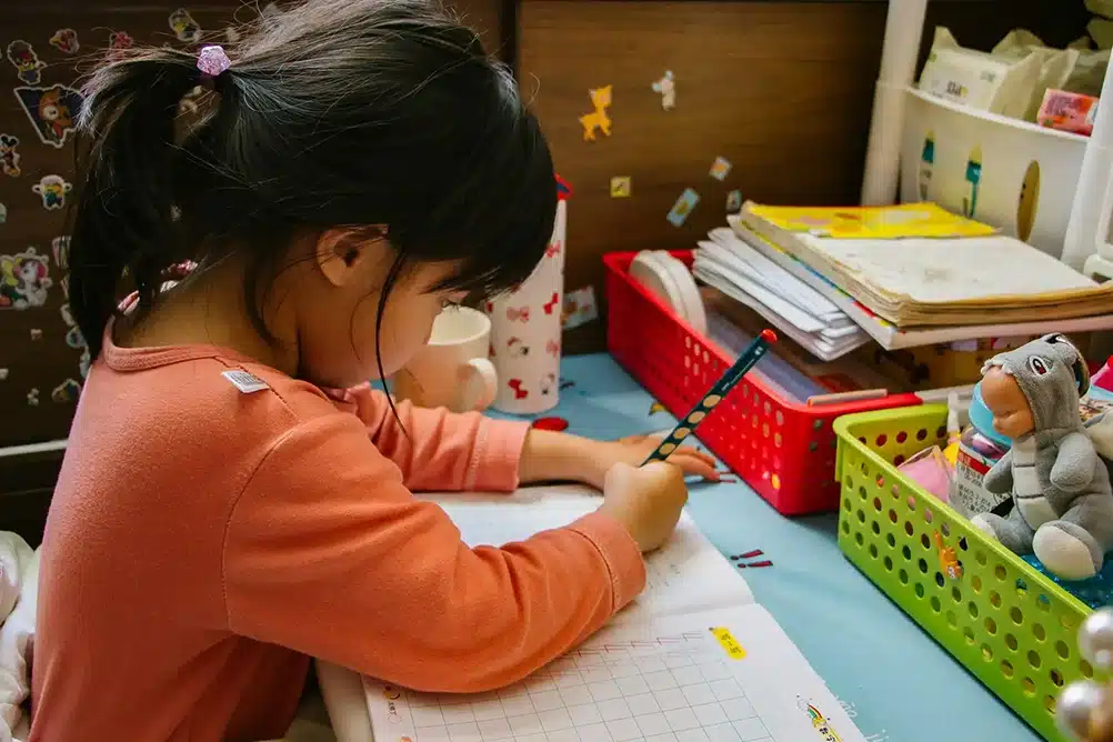 A young girl performing a school assignment.